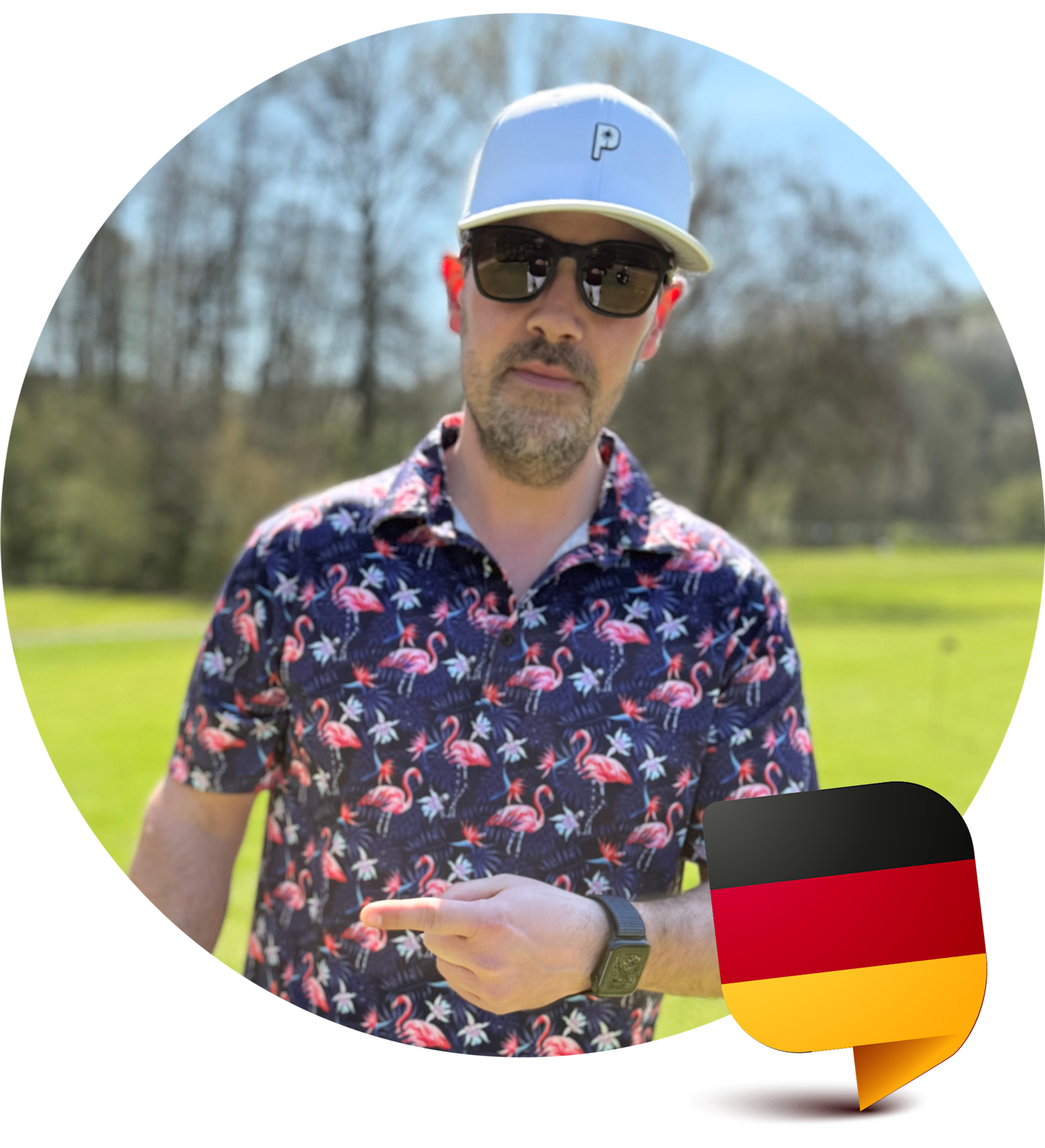 Man med solglasögon och vit keps pekar på sin handled, bär skjorta med flamingomönster, står utomhus med tysk flaggikon i hörnet.