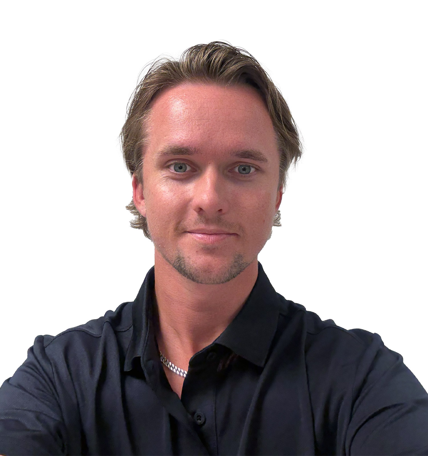 Man med kort brunt hår och svart skjorta tittar rakt fram och ler svagt mot kameran mot vit bakgrund.