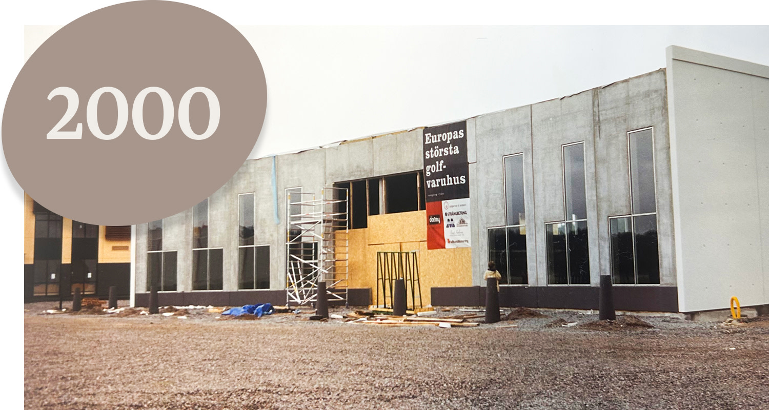Building under construction with a sign reading "Europe's largest golf superstore" and a large circle with the text "2000" in the corner.