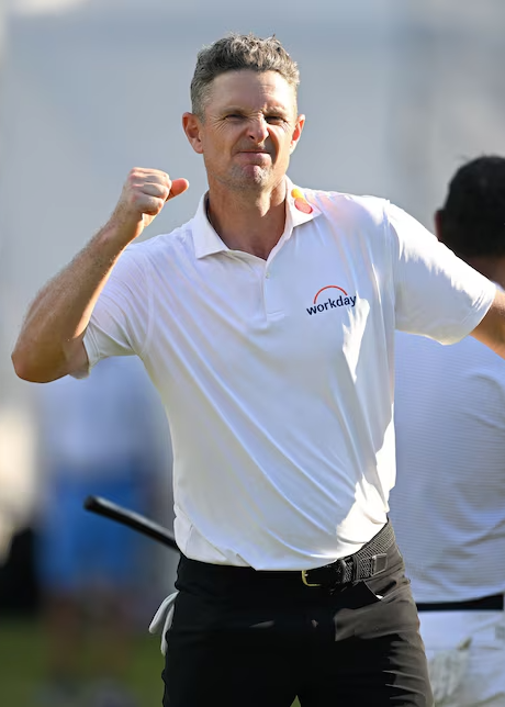 Man i vit pikétröja med "workday"-logotyp firar med knuten näve utomhus på en golfbana.