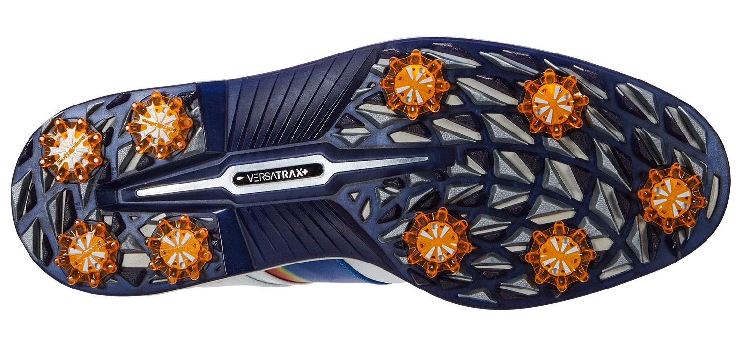 Undersida av en golfsko med blå och orange mönstrad sula, utrustad med nio Softspikes och texten "Versatrax+".