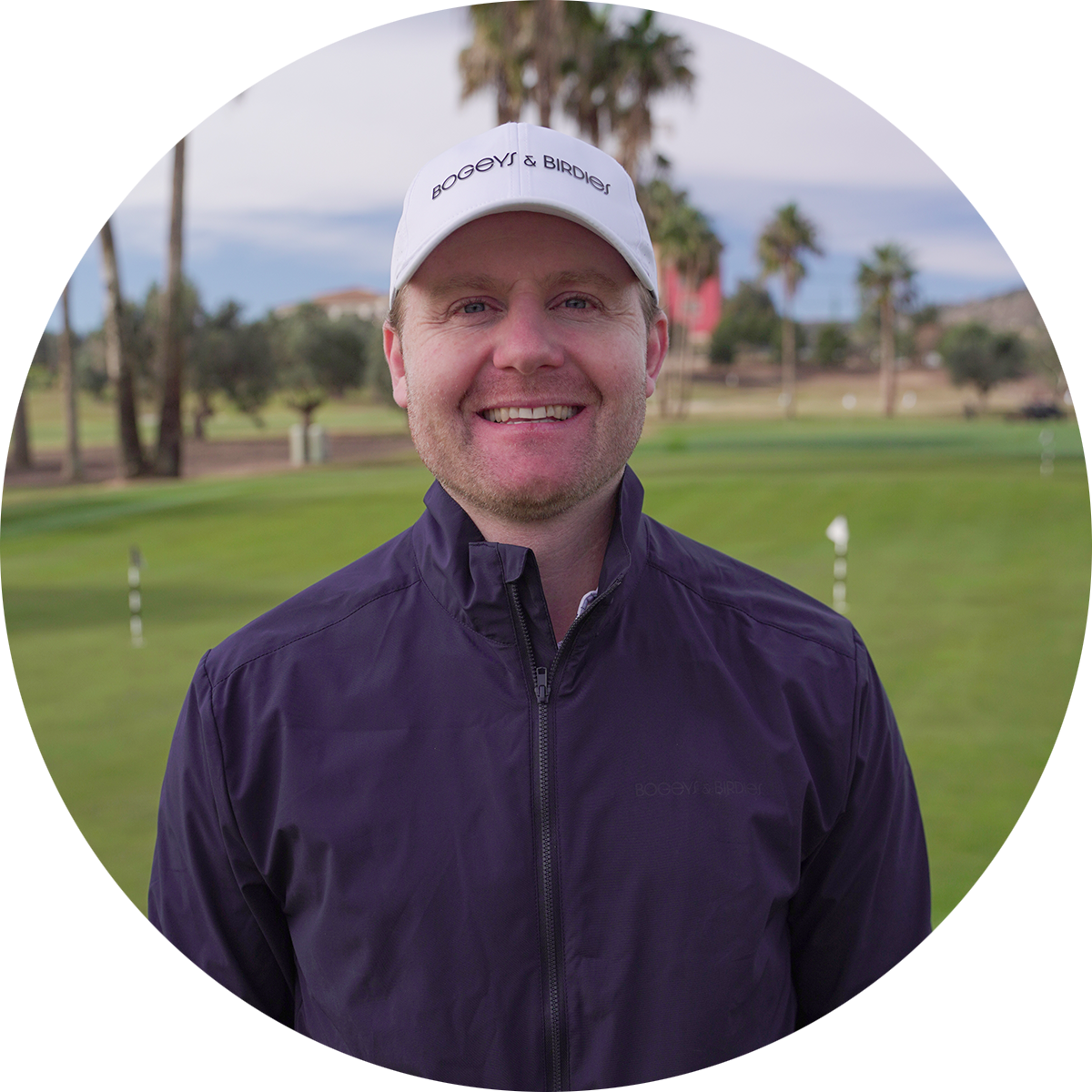 Leende man med vit keps med texten "Bogeys & Birdies" står på en golfbana med palmer i bakgrunden.