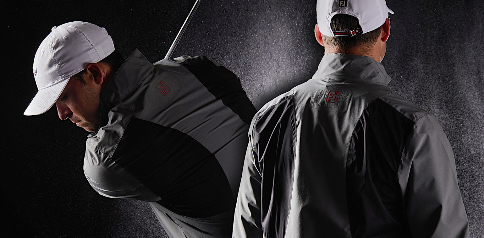 Två män i grå och svarta sportjackor och vita kepsar, en svingar en golfklubba, mörk bakgrund.