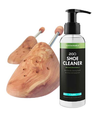 Två skoblock i trä ligger bredvid en flaska 2GO Shoe Cleaner med pump, märkt som biologiskt nedbrytbar.