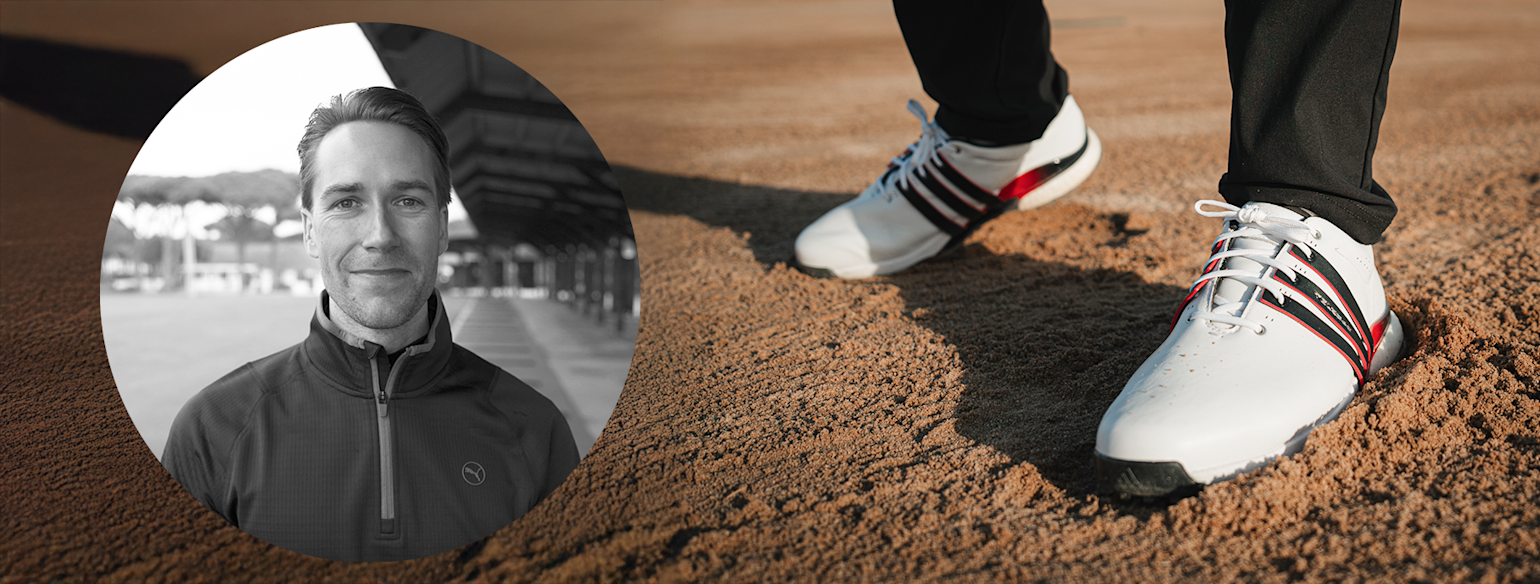 Närbild på vita golfskor med svarta och röda detaljer på sand, porträtt av leende man i träningsjacka infällt till vänster.