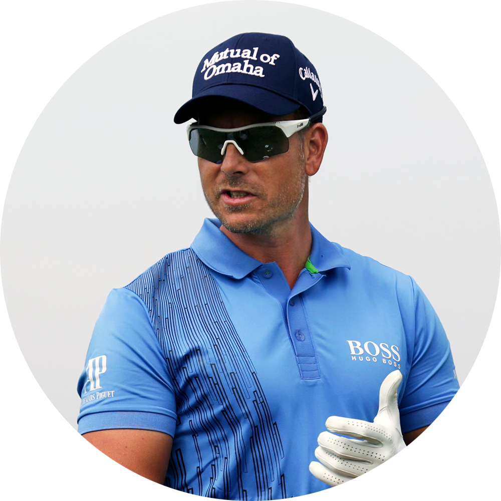 Man i blå golftröja och keps med texten "Mutual of Omaha", bär solglasögon och golfhandske, står utomhus.