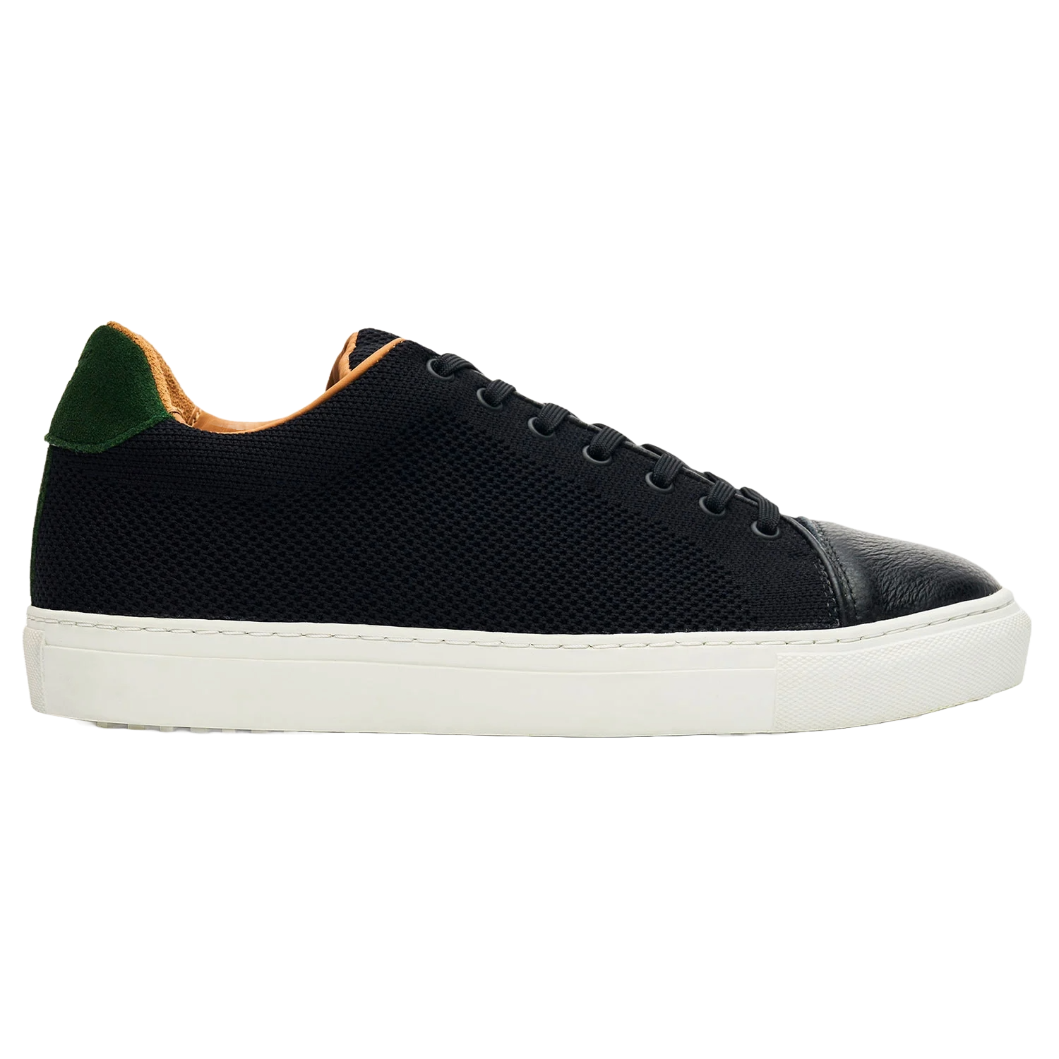 Svart sneaker med vit sula, grönt parti vid hälen och svarta skosnören, fotad från sidan mot vit bakgrund.