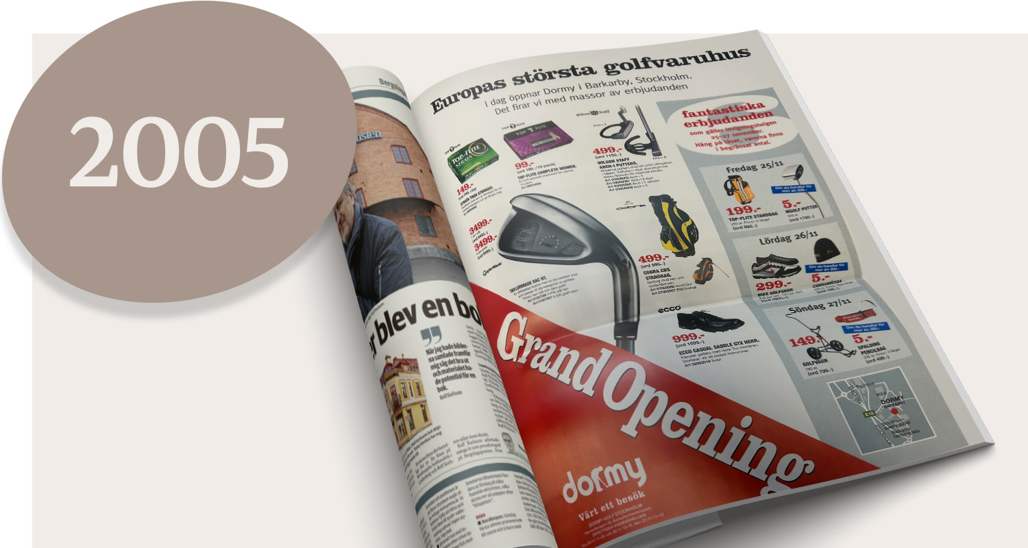 An open newspaper featuring an advert for Dormy’s golf superstore and the text “Grand Opening”, along with a large circle containing “2005”.