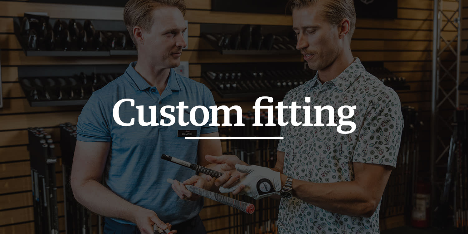 Två män håller i golfklubbor och diskuterar custom fitting i en golfbutik, med texten "Custom fitting" över bilden.