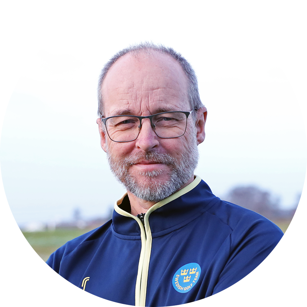 Man med glasögon och skägg står utomhus i blå jacka med "Swedish Golf Team"-logotyp, suddig bakgrund.