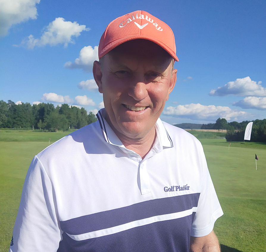 Man i vit golftröja med texten "Golf Plaisir" och orange keps med "Callaway" står på en golfbana under blå himmel.