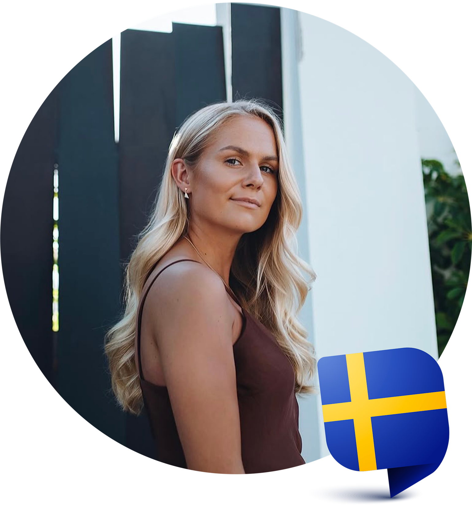 Kvinna med långt blont hår står utomhus vid ett mörkt staket, svensk flaggikon syns i hörnet.