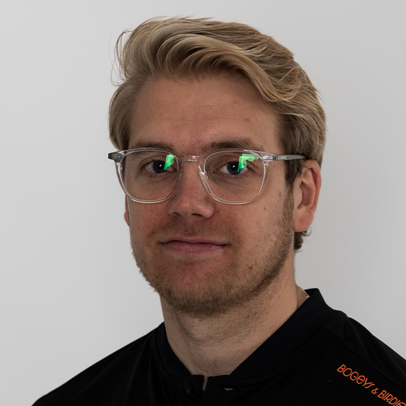 Man med blont hår och skägg bär genomskinliga glasögon och svart tröja mot vit bakgrund.